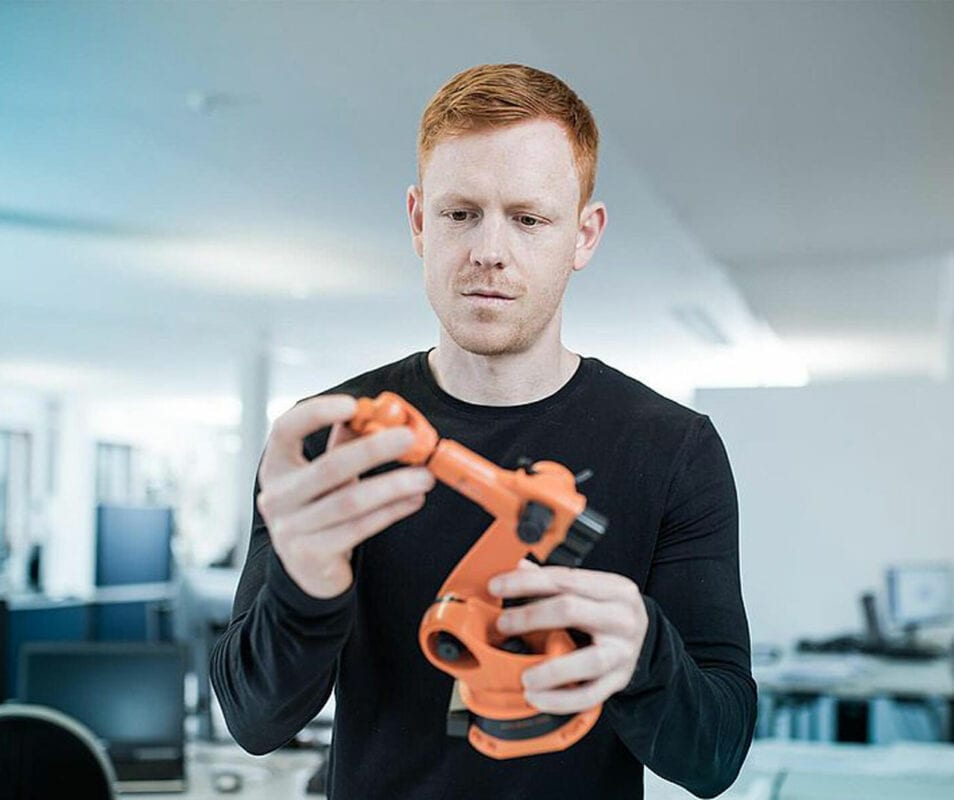 Konstrukteur der einen orangenen Roboter in der Hand hält.